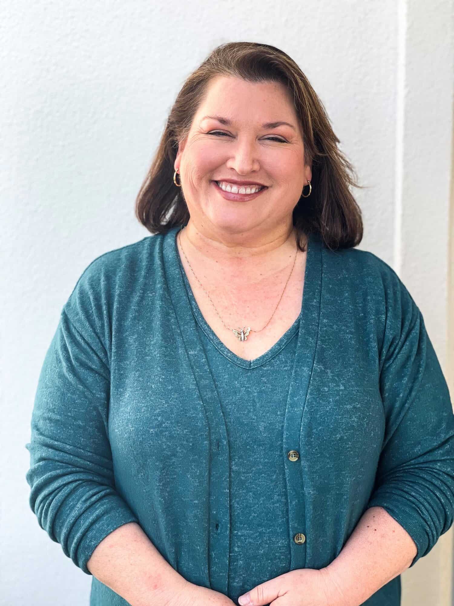 Smiling woman in teal blouse, representing client-focused mortgage lending and partnership at GMFS Partners.