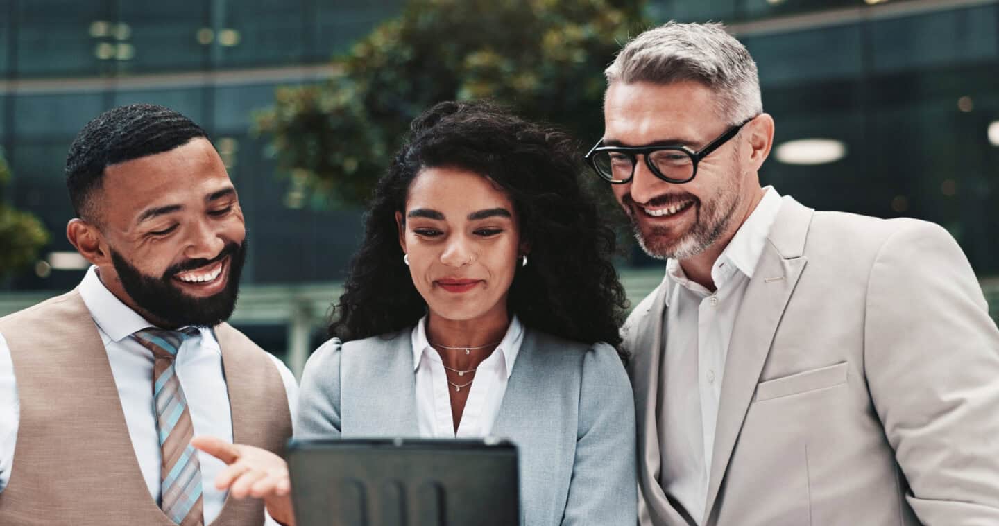 Happy professionals collaborating outdoors in business attire, emphasizing teamwork and success in corporate finance.
