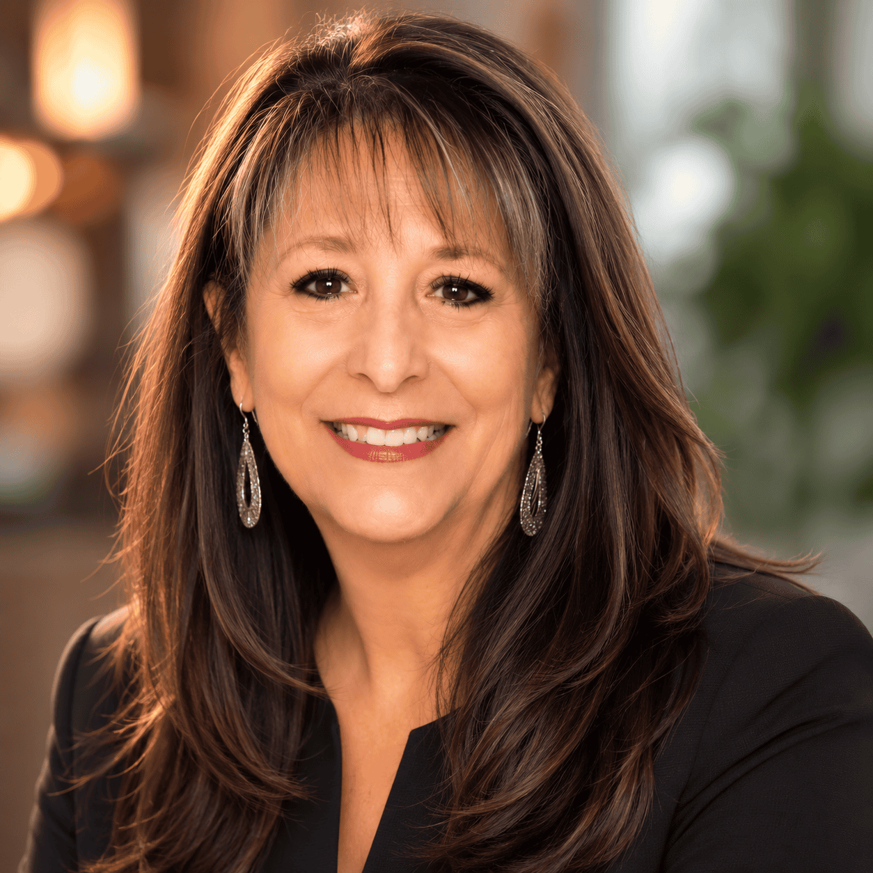 Professional portrait of Shelly Lively, smiling woman with long brown hair and earrings, in a warm, well-lit indoor setting.
