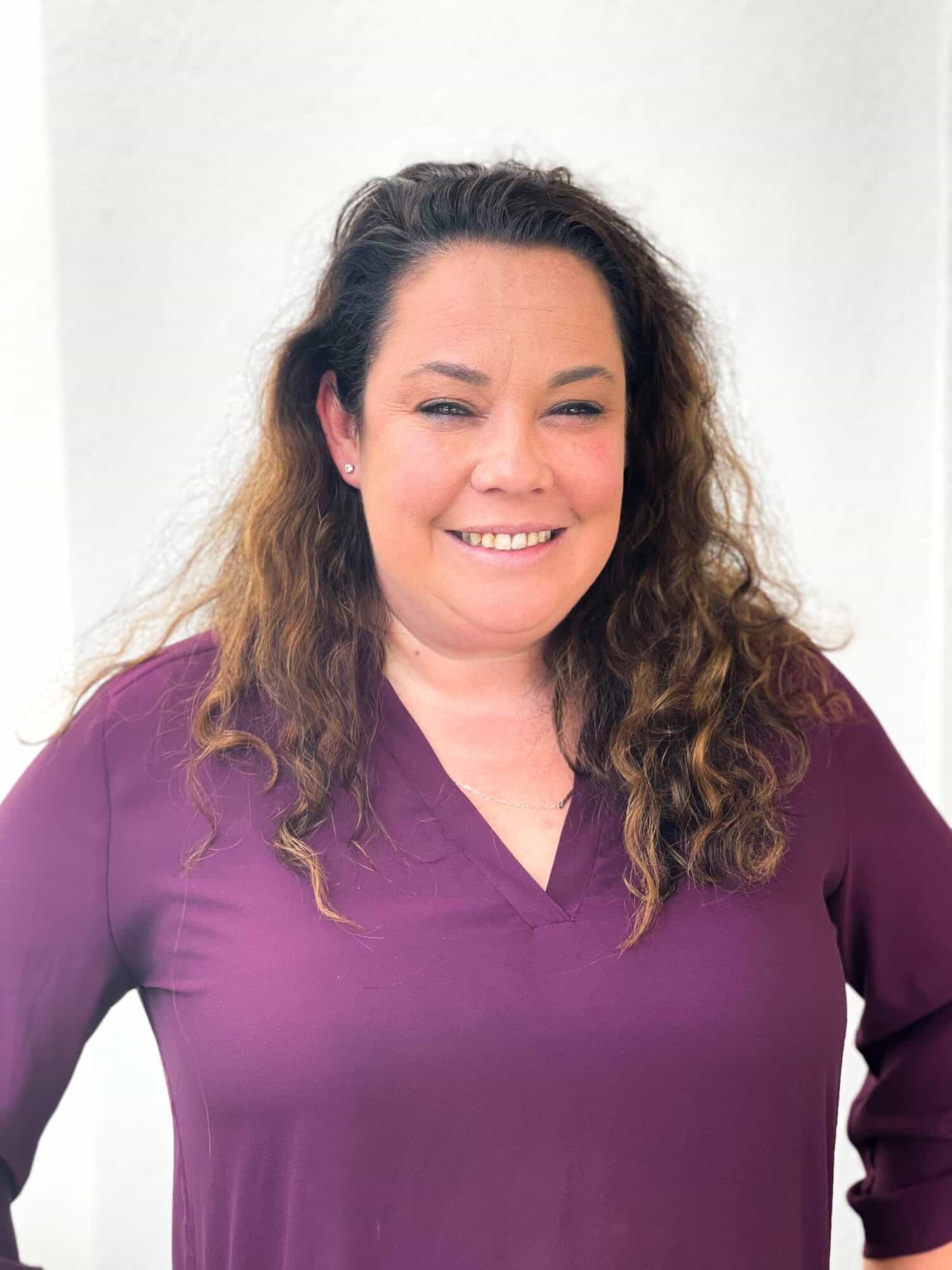 Friendly woman in professional attire smiling, representing GMFS Partners mortgage and home loan solutions.