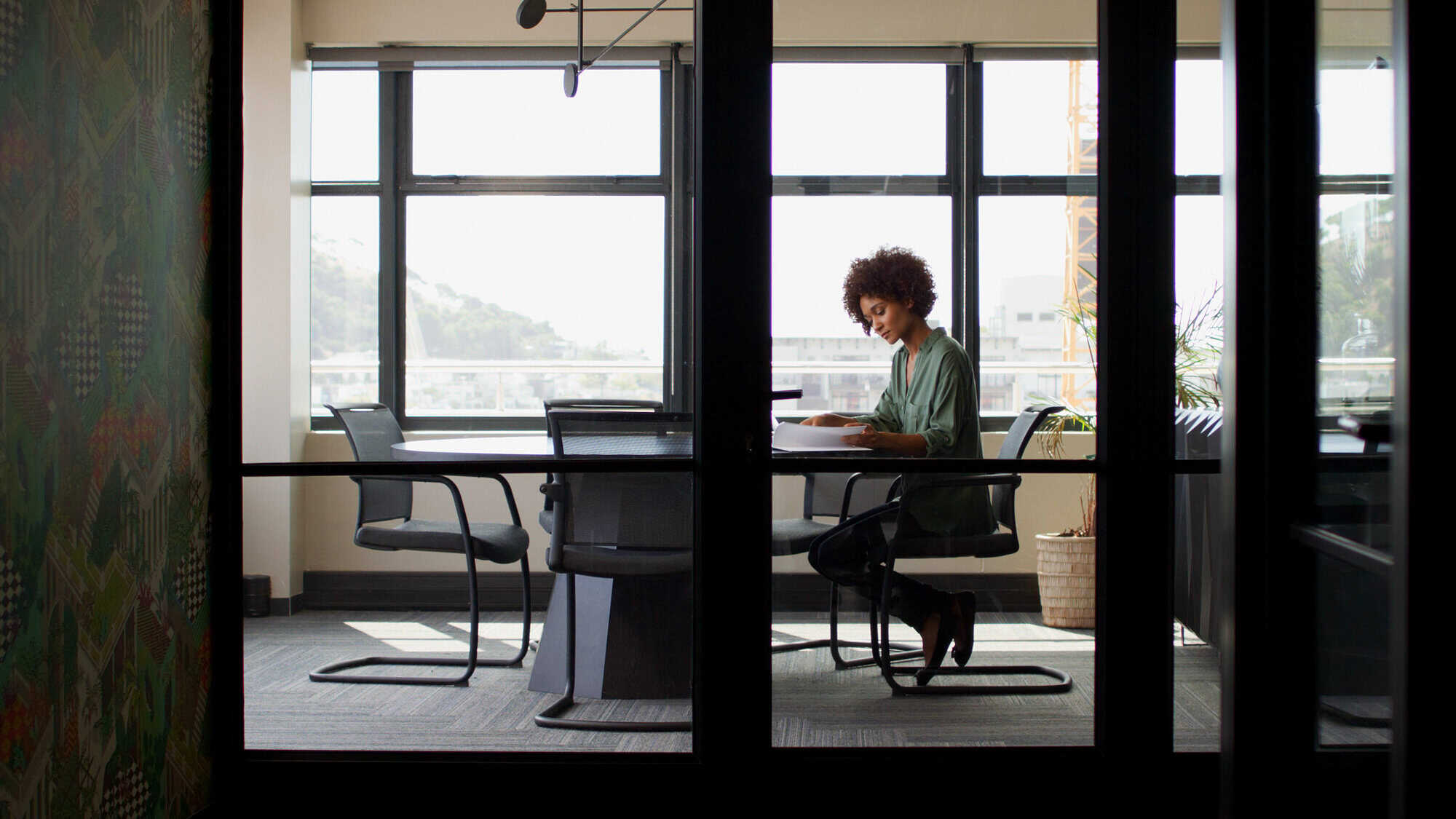 Wide Angle Shot Of Young Businesswoman Working On Looking At Document At Desk In Her Own Office