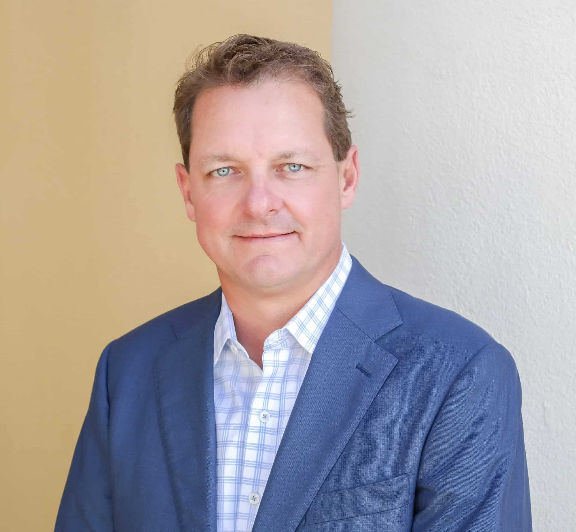 Jeff Weston, a professional financial advisor at GMFS Partners, is pictured in a business portrait. He is wearing a blue suit and white checkered shirt, standing against a neutral background.