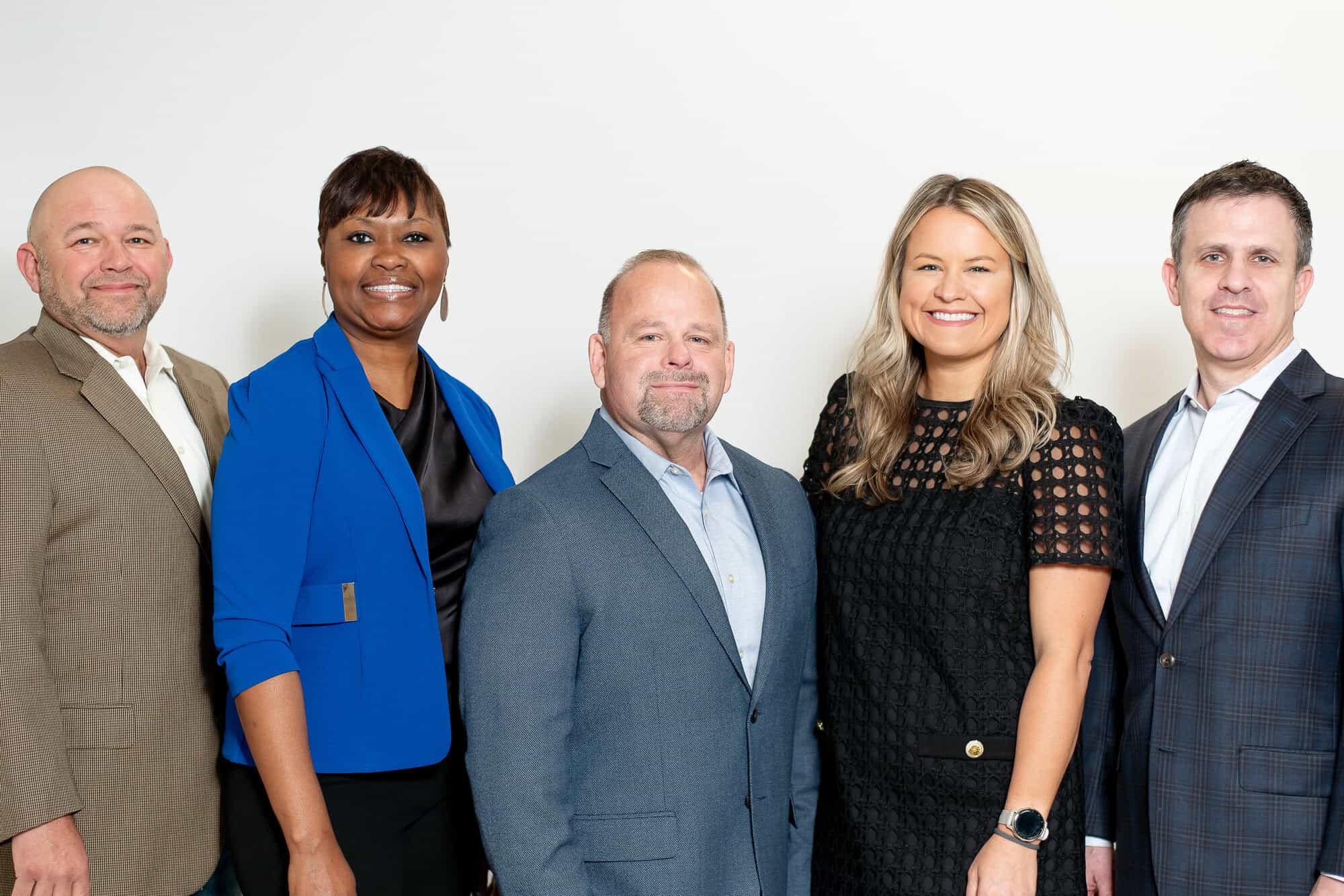 Group of diverse professionals smiling in a corporate setting, representing career opportunities at GMFS Partners.