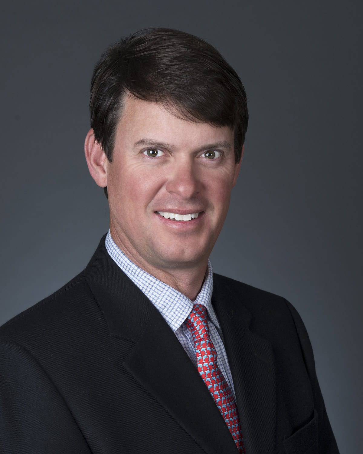 Professional portrait of Tee Brown, a mortgage expert at GMFS Partners, smiling confidently in formal business attire.
