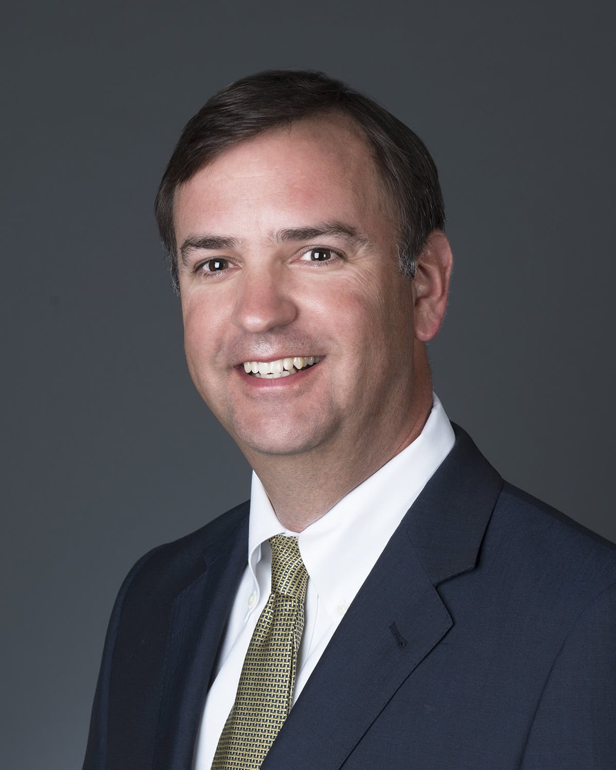 Mortgage professional smiling in formal suit at GMFS Partners office.